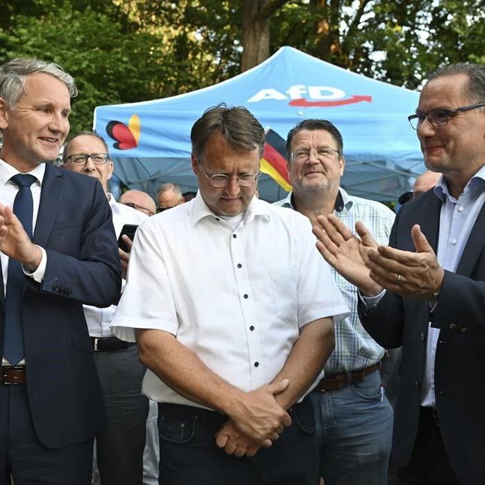 After a far-right victory in German county, a man in neo-Nazi clothing hands balloons to children